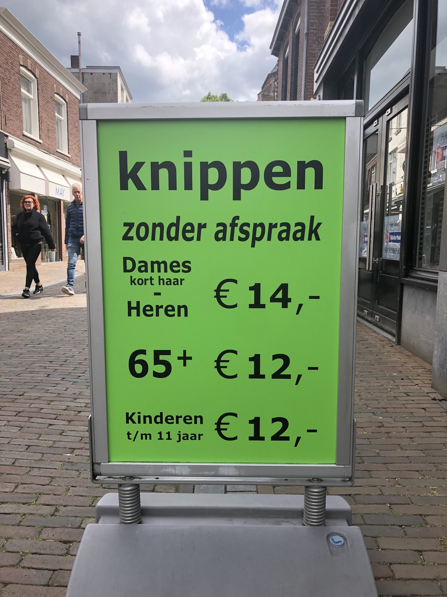 Het groene stoepbord van Kapsalon Castal met de tekst knippen zonder afspraak en de prijzen, op de klinkers van de Fonteinstraat